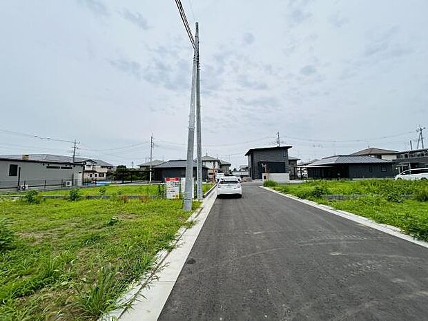 前面道路が幅広く車の出入りがしやすい環境です。周囲は落ち着いた住宅地でゆとりある区画が広がっています。電柱や配線も整っておりインフラ面も安心です。現地の状況が一目で確認できる写真です。