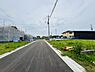 その他：新しく整備された前面道路が印象的な現地写真です。まっすぐ伸びる道路が開放感を与えます。周囲には建築中の建物や空き区画も確認できます。住環境の変化や新たな街並みの形成を感じさせる一枚です。