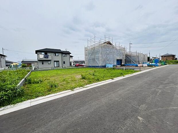 広々とした前面道路が特徴的な区画です。周囲には新築住宅や戸建て住宅が立ち並び開放感があります。現地の雰囲気を直接ご確認いただける写真です。道路と敷地の関係も分かりやすく掲載しています。