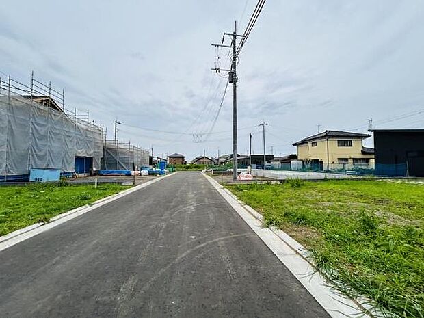 舗装された前面道路が敷地へスムーズなアクセスを実現しています。住宅が立ち並ぶ落ち着いた環境も魅力的です。敷地の広がりを感じられる景観となっています。電柱や配線もきちんと整備されています。