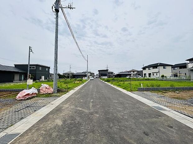 現地前面道路は整備された舗装道路がまっすぐに伸びており車両の通行も快適です。周囲には新しい住宅が建ち並び周辺環境も落ち着いた印象です。道路幅も十分に確保されておりゆったりとした空間が広がっています。