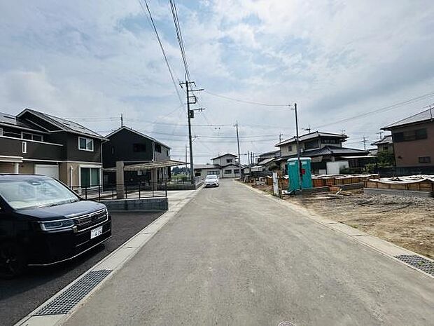 前面道路が広々と確保されており車の通行もスムーズに行えます。落ち着いた住宅街の雰囲気が感じられる現地写真です。周囲に新しい住宅が建ち並び整然とした景観になっています。