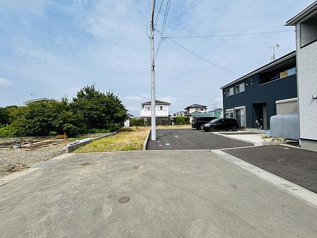 前面道路が広々としており車の出入りがしやすい現地写真です。周囲は落ち着いた住宅街となっています。敷地の隣は緑も感じられる住環境です。電柱や配線も整然としており安心感があります。