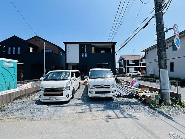 黒を基調とした外観が洗練された印象を与えます。並列駐車が可能な広い駐車スペースが確保されています。周囲には新しい住宅が建ち並び整った街並みが特徴です。建物のファサードがシンプルですっきりとしています。