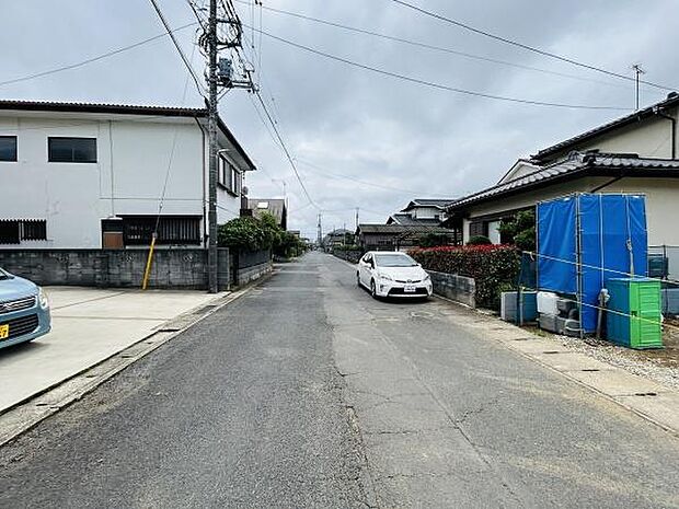 前面道路はすれ違いもしやすい幅があります。電柱や配線も整然と設置されている印象です。周囲には住宅が並び近隣とのバランスも整っています。