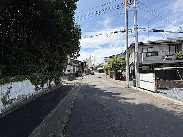 前面道路は広さが確保されており車の出入りも安心して行えます。周囲には住宅が整然と並び落ち着いた雰囲気が感じられます。道路沿いの緑も印象的で街並みにやさしい印象を与えています。