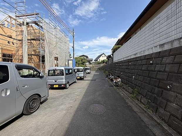 前面道路は幅があり車の通行や駐車がしやすい環境です。道路沿いには建築物が並び落ち着いた住宅地の雰囲気があります。空の抜け感も感じられるロケーションです。