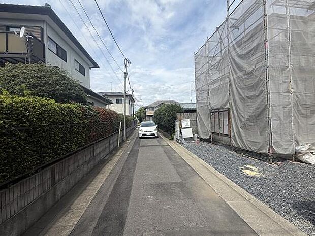 現地写真は周囲の住宅や工事中の建物が確認でき前面道路は幅員がしっかりと確保されています。電柱や植栽も整然としており道幅や周辺環境の様子が把握しやすいです。