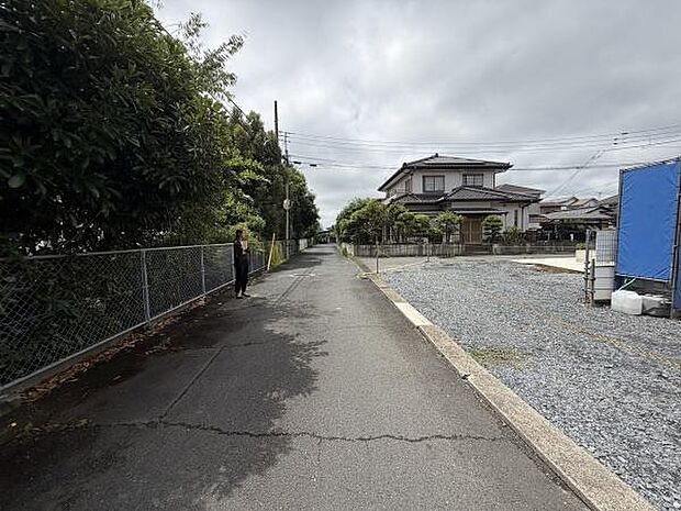 現地前面道路はまっすぐに続き歩道と車道の区切りがしっかりしています。周囲には住宅が建ち並び落ち着いた印象です。道路幅も確保されており交通の利便性も期待できます。周囲の緑が景観にやさしさを加えています。