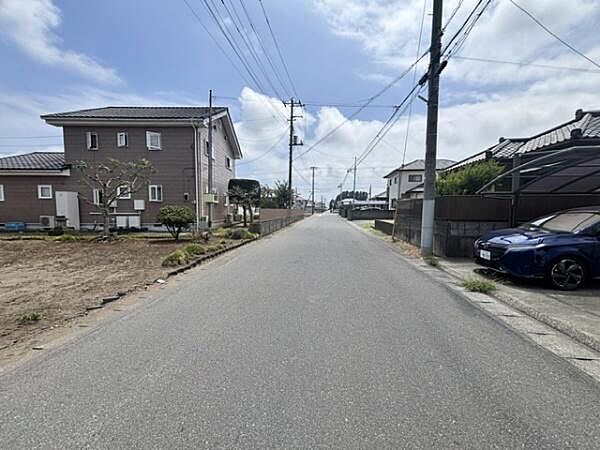 前面道路は幅員が広く車の通行もスムーズに行えます。見通しがよく駐車や出入りも快適に行えます。周囲には住宅が立ち並んでおり落ち着いた雰囲気が感じられます。空も広く開放感がある現地写真です。