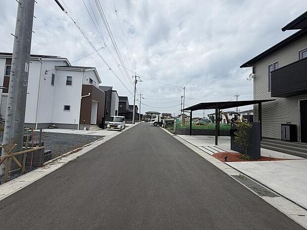 前面道路は幅が広く車の出入りがしやすい印象です。周囲には新しい住宅が並び整然とした街並みが特徴的です。道路の舗装状態も良好で清潔感があります。電柱や配線も整然と配置されています。