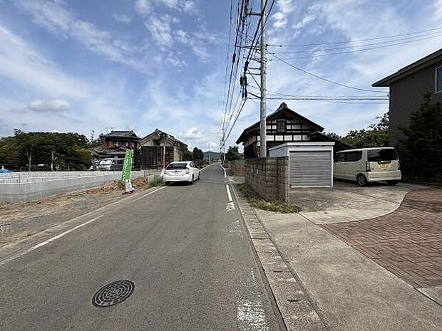 前面道路は舗装されており車の出入りがしやすい環境です。周囲は落ち着いた雰囲気で道路沿いには電柱などが整備されています。
