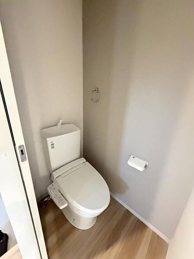 シンプルで清潔感のあるトイレ空間です。温水洗浄機能付き便座が設置されています。使いやすいレイアウトで落ち着いた色合いが特徴です。壁面にはペーパーホルダーも完備されています。