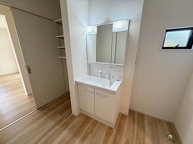 洗面台・洗面所はシンプルで使いやすいデザインです。明るい照明が備わっており鏡も大きめです。収納スペースも確保されているため整理整頓がしやすいです。床と壁の色合いが調和しています。