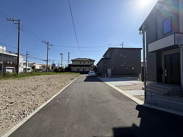周辺に電柱や建物が整然と並ぶすっきりとした前面道路の現地写真です。道路幅もしっかり確保されており見通しの良い印象があります。舗装も新しく生活の利便性が感じられます。