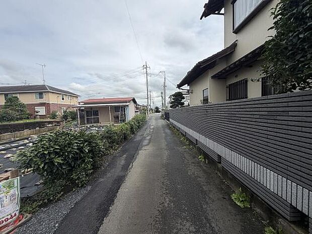 現地の前面道路は落ち着いた雰囲気があり周囲には住宅が立ち並んでいます。車の通行もスムーズで視界も開けています。敷地前の道路は舗装されていて利用しやすい印象です。