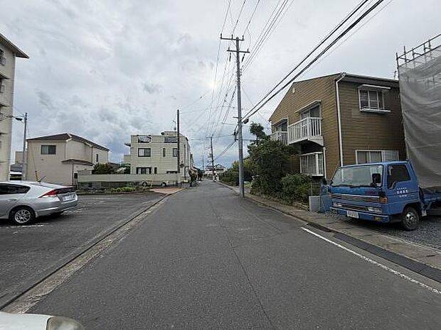 前面道路は幅員が広く車の出入りがしやすい環境です。物件周辺は整った街並みが印象的です。周囲には駐車スペースも確保されています。電柱や配線も整然としていて全体的に清潔感があります。