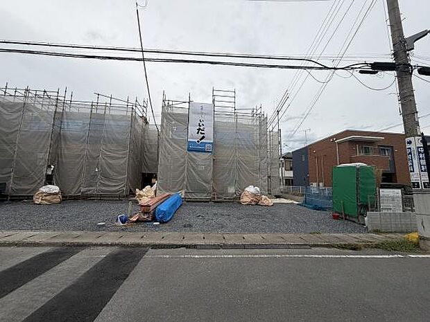 建築中の物件でこれからの完成が楽しみな現場です。敷地前はアスファルト舗装されており前面道路も広めです。工事用の簡易トイレや防護ネットの設置が確認できます。