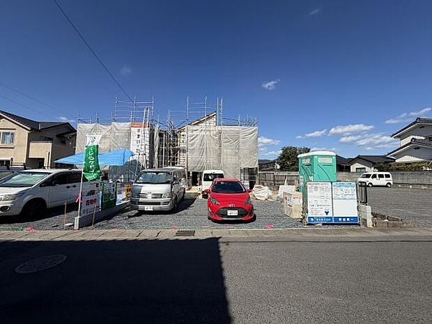 青空が広がる中工事中の建物が存在感を示しています。敷地内には複数台の車が駐車可能でスペースもゆとりがあります。周囲は住宅が立ち並ぶ落ち着いた雰囲気です。整備された駐車場も利用できます。