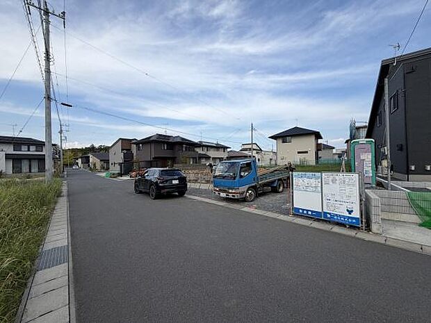 現地前面道路は広々としておりゆとりある通行が可能です。周囲には新しい住宅が並び落ち着いた雰囲気が魅力です。建設中のため将来的な街並みの変化も期待できます。