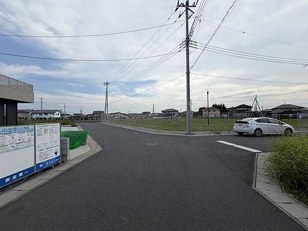 前面道路は幅員が広く開放的な雰囲気が感じられます。周辺は住宅が点在しており落ち着いた印象です。きれいに舗装された道路が整然としています。空が広く見渡せるのも特徴的です。