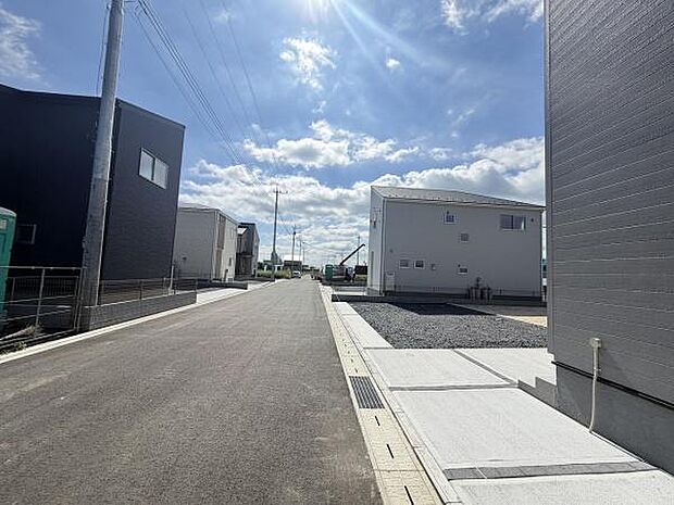 前面道路が広く車の出入りがしやすい環境です。周囲は新しい建物が並びすっきりとした印象を受けます。晴れた日の空が広がり明るさを感じられます。電柱や配線も整然と配置されています。