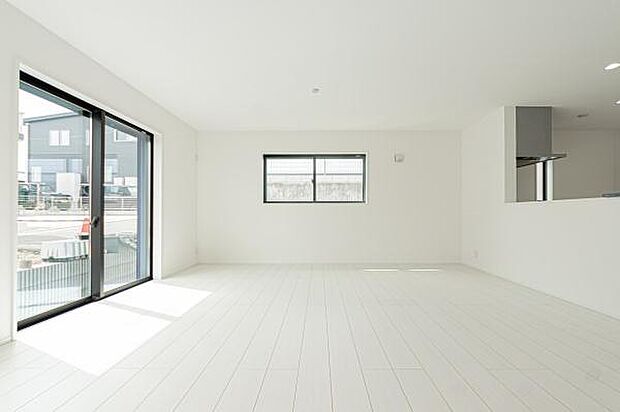 自然光が溢れる明るいLDK。白を基調とした空間に、庭の緑とウッド調のフロアが優しいコントラストを描き、家族の笑顔が弾む開放的な暮らしを演出します。