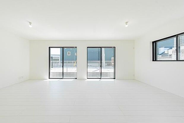 自然光が溢れる明るいLDK。白を基調とした空間に、庭の緑とウッド調のフロアが優しいコントラストを描き、家族の笑顔が弾む開放的な暮らしを演出します。