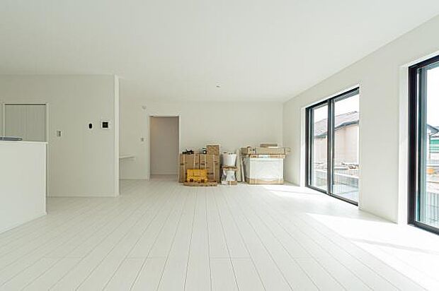 自然光が溢れる明るいLDK。白を基調とした空間に、庭の緑とウッド調のフロアが優しいコントラストを描き、家族の笑顔が弾む開放的な暮らしを演出します。