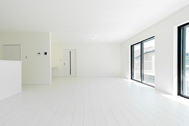 自然光が溢れる明るいLDK。白を基調とした空間に、庭の緑とウッド調のフロアが優しいコントラストを描き、家族の笑顔が弾む開放的な暮らしを演出します。