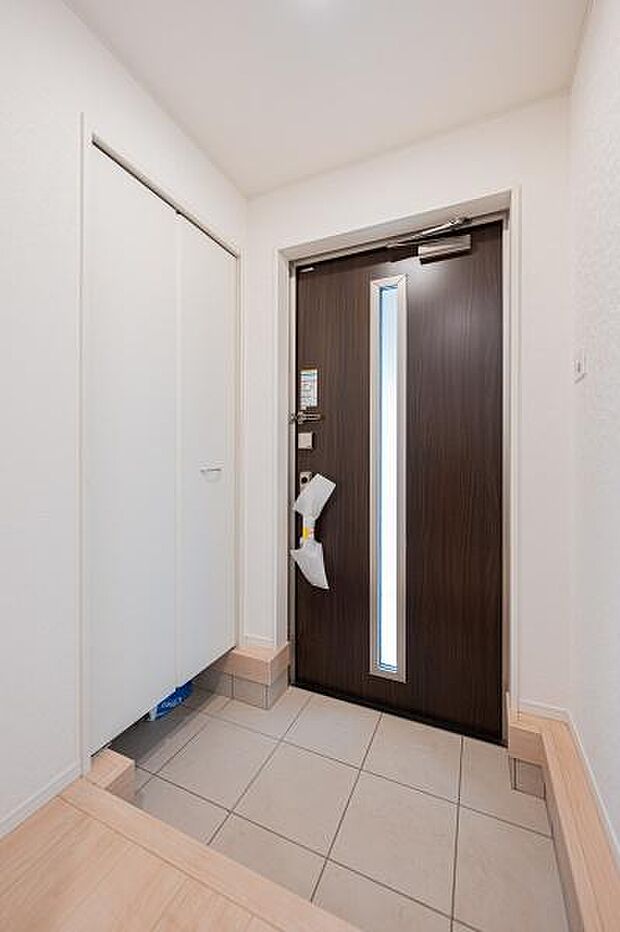 帰宅した瞬間に木の質感がほっと心を和ませる玄関ホール。家族の温かな団らんへと自然につながる、心地よい風と光が通る住まいです。