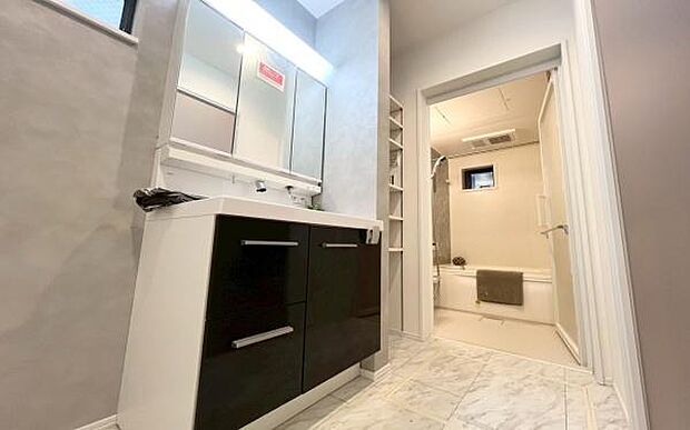 《洗面化粧台》　■清潔感あふれるパウダールーム。明るい照明付きの三面鏡で、メイクやヘアセットもスムーズに。隣には洗濯機置場も完備し、使い勝手の良い空間です。