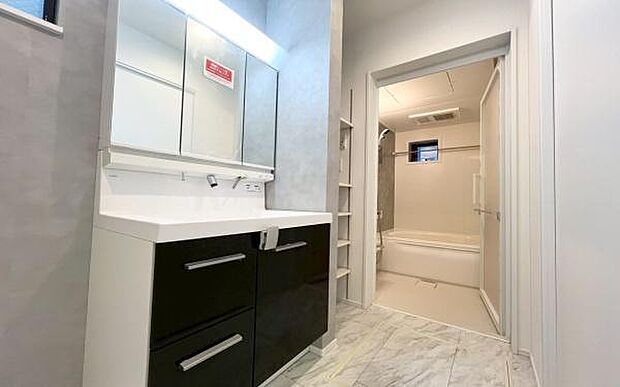 《洗面化粧台》 ■清潔感あふれるパウダールーム。明るい照明付きの三面鏡で、メイクやヘアセットもスムーズに。隣には洗濯機置場も完備し、使い勝手の良い空間です。