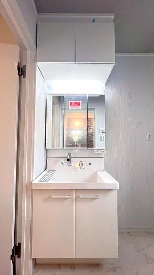 《洗面化粧台》　■洗面化粧台の鏡は、メイクや髭剃りに便利な三面鏡タイプ。開いて合わせ鏡としても使用できます。鏡の裏側は収納スペースとして利用でき、小物などの保管に便利な棚も付いています。