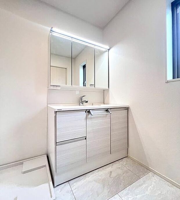 《洗面化粧台》　■洗面化粧台の鏡は、メイクや髭剃りに便利な三面鏡タイプ。開いて合わせ鏡としても使用できます。鏡の裏側は収納スペースとして利用でき、小物などの保管に便利な棚も付いています。