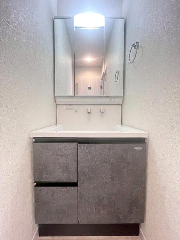 《洗面化粧台》 ■洗面化粧台の鏡は、メイクや髭剃りに便利な三面鏡タイプ。開いて合わせ鏡としても使用できます。鏡の裏側は収納スペースとして利用でき、小物などの保管に便利な棚も付いています。
