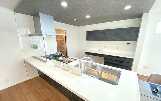 《ペニンシュラキッチン》　■白いカウンターが、毎日の料理をちょっと特別にする。ダークトーンの収納が空間を引き締め、暮らしに上質なリズムを生み出すペニンシュラドキッチン。