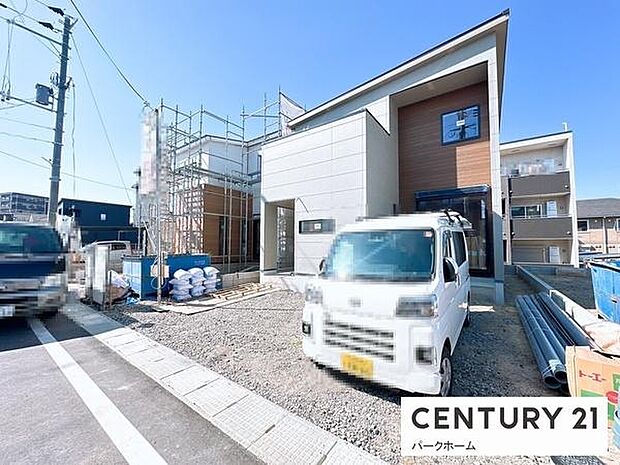 白いボーダーパネルとナチュラルなウッド調外壁を組み合わせた、個性際立つモダンデザインの新築住宅。