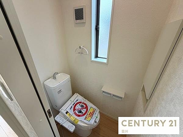 清潔感のある白で統一された2階のトイレ空間です。温水洗浄便座や手洗い機能、換気用の小窓を備えているほか、埋込式の棚収納付きでペーパー等もスマートに保管できます。