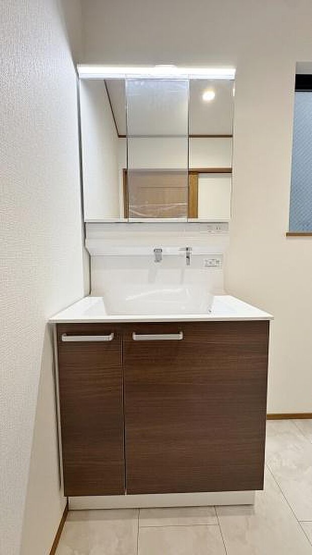 《洗面化粧台》　■洗面化粧台の鏡は、メイクや髭剃りに便利な三面鏡タイプ。洗面台サイドには収納スペースとして利用でき、小物などの保管に便利な棚も付いています。