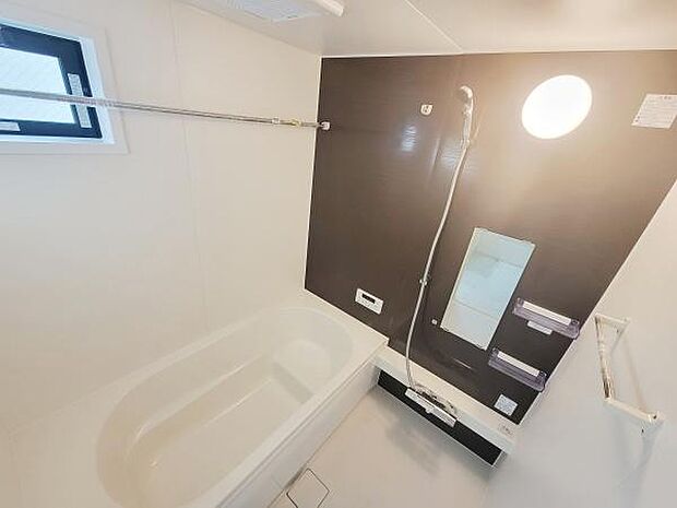 白を基調にした清潔感のあるバスルームです。ダークカラーのアクセントパネルが空間を引き締めています。浴室乾燥機や大きな鏡など使いやすさに配慮された設計です。窓が付いているので換気も便利です。
