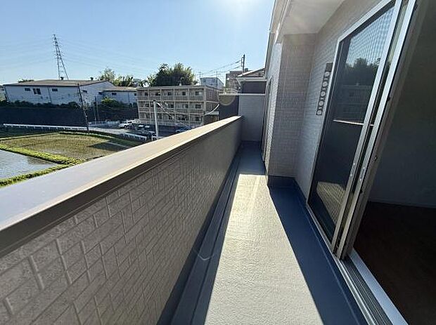 広々としたバルコニーで開放感があります。日当たりの良さが感じられる空間です。手すり部分も高さがあり安心感があります。外の景色も見渡せるロケーションです。