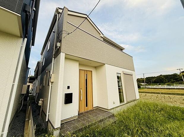 シンプルな外観デザインが特徴の一軒家です。玄関にはゆったりとしたポーチがあり出入りがしやすいです。周囲は緑が広がり落ち着いた環境に位置しています。窓も大きく自然な採光が感じられます。