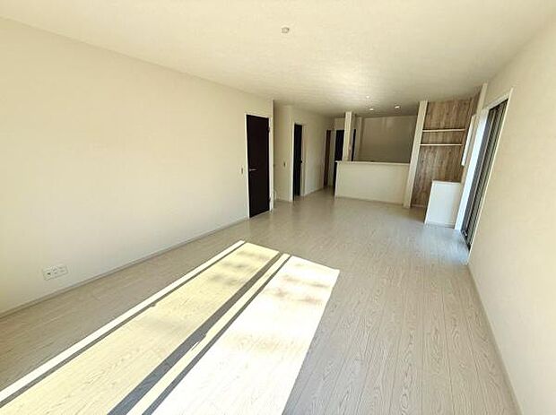 明るい日差しがたっぷり差し込むリビングです。シンプルな内装で空間に広がりがあります。床の色が落ち着いた雰囲気を演出しています。隣接したキッチンも見渡せる配置です。開放感のある設計が魅力的です。