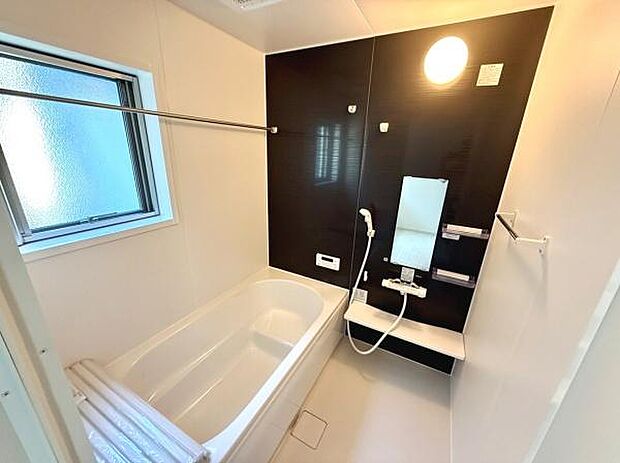 窓付きでしっかりと換気ができる浴室です。シンプルなデザインが特徴的でお手入れもしやすい印象です。壁面パネルの色合いが空間を引き締めています。ミラーや棚も設置され使い勝手にも配慮されています。