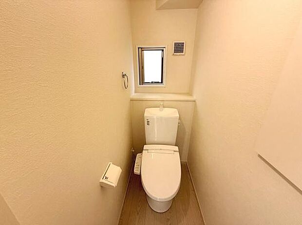 コンパクトな空間にシンプルなデザインのトイレが設置されています。小窓があり明るさと換気が確保されています。壁紙の色合いが落ち着いた雰囲気を演出します。