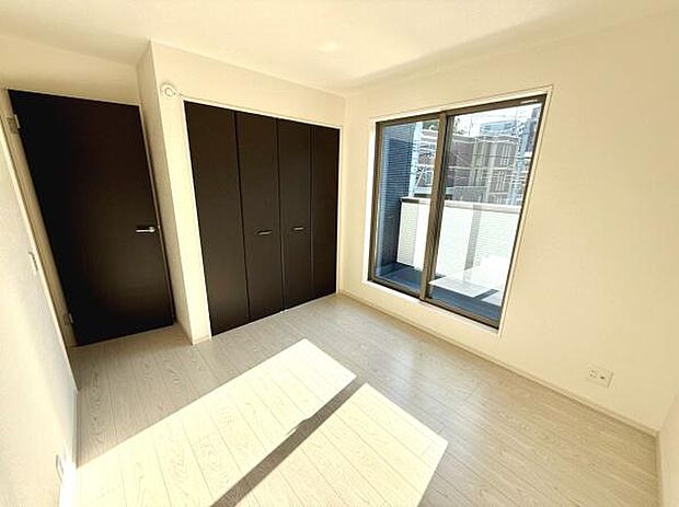 明るい光が差し込む洋室です。広々としたクローゼットが備わっています。窓から外の様子がよく見えます。床の色合いが空間をすっきりと見せています。