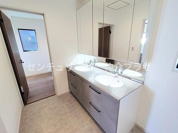 広々とした洗面所には収納力があるキャビネットが設置されています。清潔感あふれる空間で毎日の準備がスムーズになります。大きなミラーが明るさを増し広さを感じさせます。