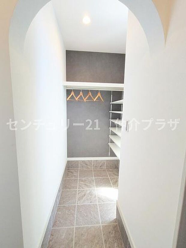 アーチ型の入り口が魅力的な収納スペースです。シンプルで機能的なデザインが特徴です。服や小物をすっきり整理できる棚とハンガーパイプが便利です。明るい照明で中までしっかり見渡せます。