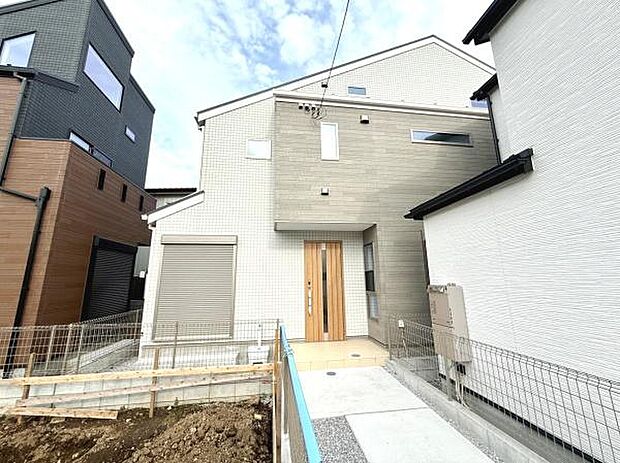 落ち着いた色合いの外観が現代的な雰囲気を演出しています。周囲には同じような新しい住宅が立ち並び地域全体が整っています。玄関までのアプローチも広く設計されており開放感があります。